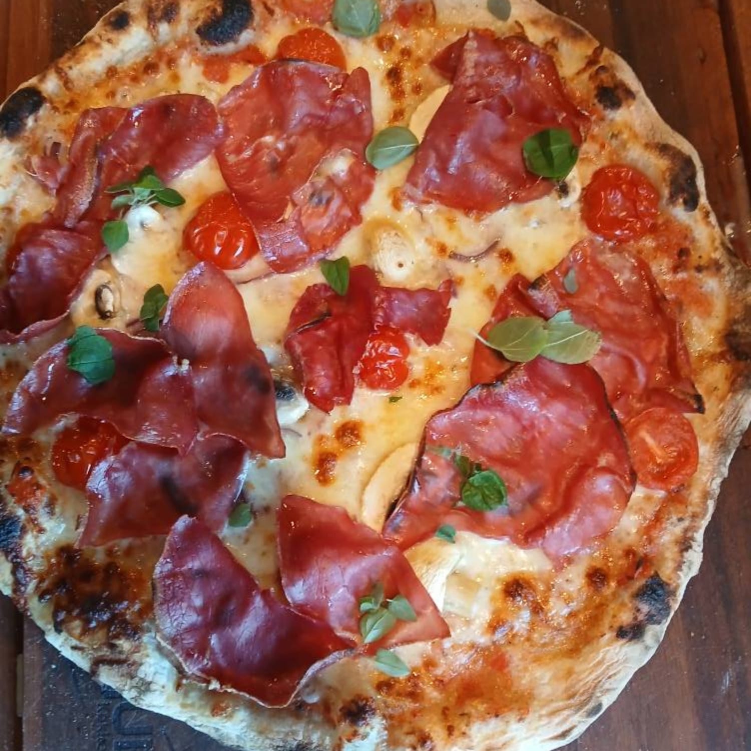 Hjemmelavet pizza med skinke, ost, tomat og basilikum