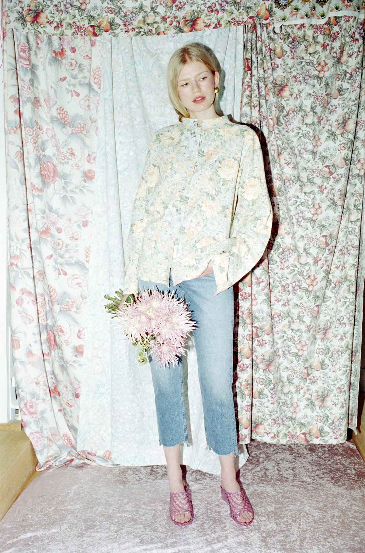 Woman in floral shirt and jeans holding flowers